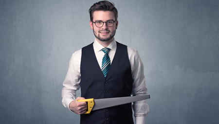 Businessman holding tool with grey grunge background.の写真素材