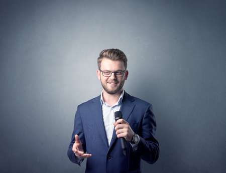 Businessman speaking into microphone with blue background