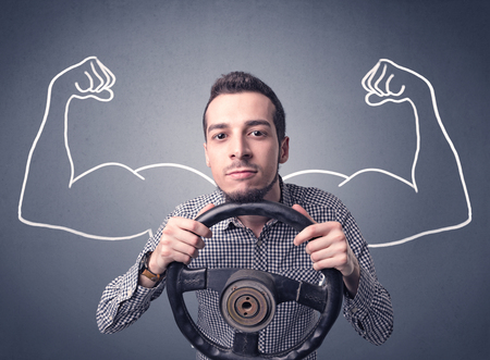 Young man holding black steering wheel with muscly arms drawn next to himの写真素材