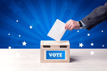 Voting hand with ballot and wooden boxの写真素材