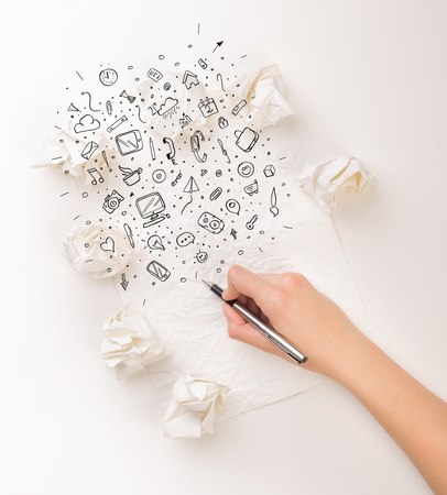 Female hand next to a few crumpled paper balls drawing mixed media iconsの写真素材