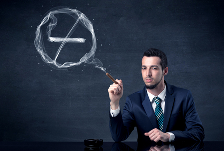 Businessman smoking cigarette and the smoke forms a no smoking sign.の写真素材