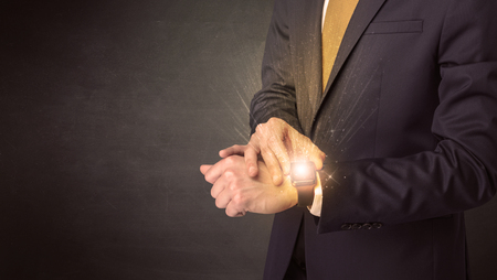 Businessman wearing smartwatch with shiny rays on it.の写真素材