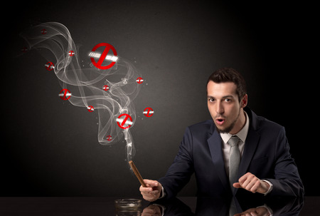 Businessman smoking with colored no smoking symbols nearby.の写真素材