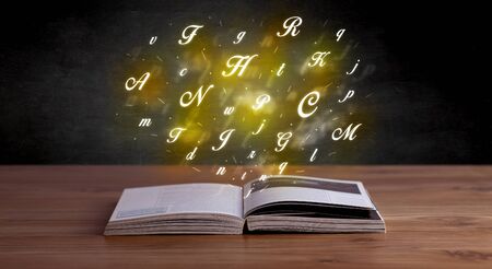Glowing yellow alphabet letters coming out of an open bookの写真素材