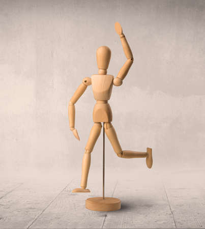 Wooden mannequin posed in front of a greyish backgroundの写真素材
