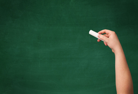 A mature hand writing or drawing on a clean green blackboard with a white chalk.の写真素材