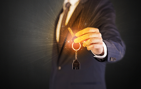 Formal man hand over shiny keys with dark backgroundの写真素材