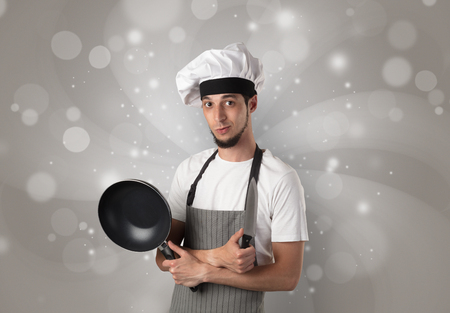 Male cook with kitchen tools and shiny grey wallpaperの写真素材
