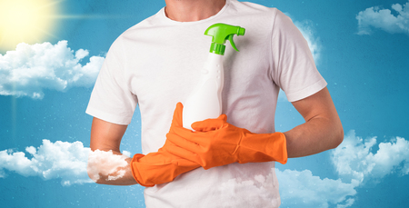 Sunny and cloudy concept with male housekeeper and orange gloves on his handの写真素材