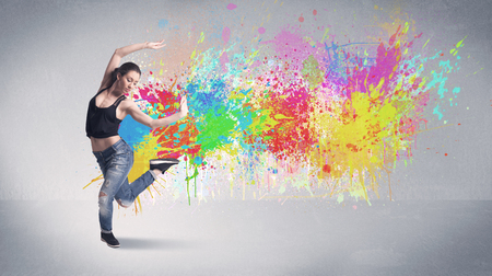 A funky contemporary hip hop dancer dancing in front of grey background with colorful bright paint splatter conceptの写真素材
