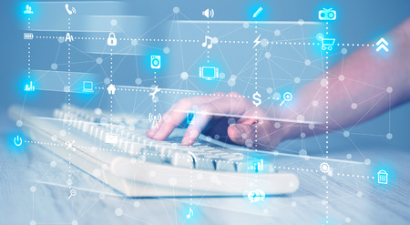 Hand pressing keyboard with high tech media icons and symbols