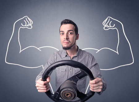 Young man holding black steering wheel with muscly arms drawn next to himの写真素材