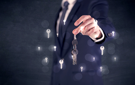 Businessman in suit holding keys with keys graphics around and dark backgroundの写真素材