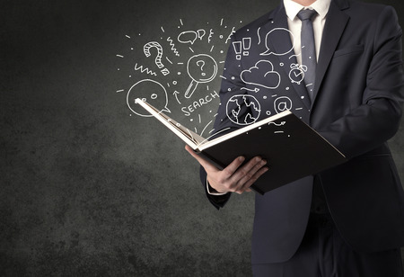 Businessman holding book with doodle drawings and signs.の写真素材