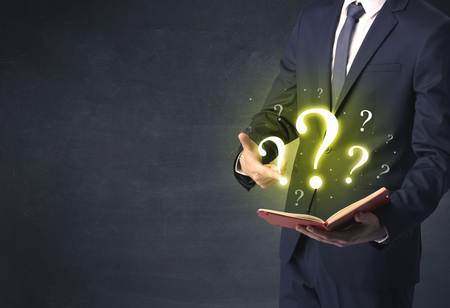 Businessman holding a book with question mark symbol.の写真素材