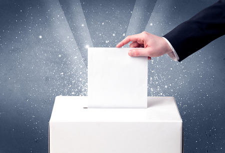 Ballot box with person casting vote on sparkling backgroundの写真素材