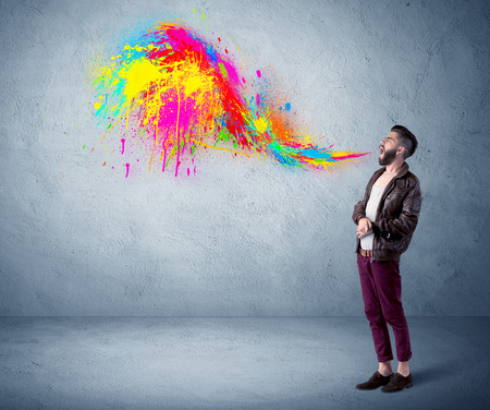 A funny hipster person in casual urban clothing shouting bright colorful paint on city wall conceptの写真素材