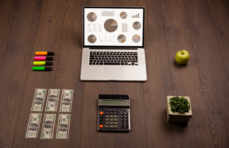 Pie chart graph icons and symbols on laptop screen with office accessoriesの写真素材