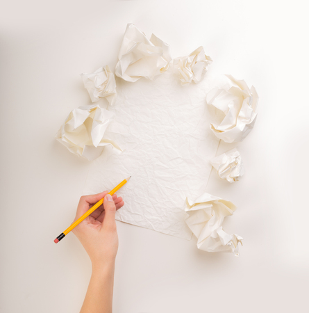 Female hand trying to write next to a few crumpled paper balls の写真素材