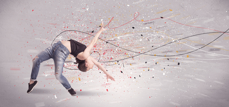 A young contemporary energetic dancer in action in front of a grey wall background with lines, spray dots and splatter conceptの写真素材