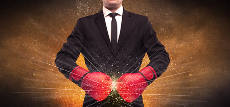 A successful powerful business person in red boxing gloves concept with illustrated power lines and pieces falling apart in front of explosion.の写真素材