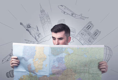 Handsome young man holding a map with famous sightseeing destinations above his headの写真素材