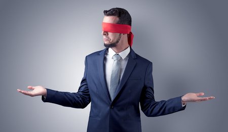 Covered eye, indecisive businessman standing blind in front of a wallの写真素材