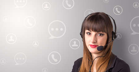 Young female telemarketer with white speech bubbles around herの写真素材