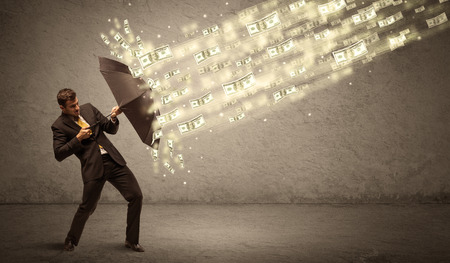 Business man holding umbrella against dollar rain concept on grungy backgroundの写真素材