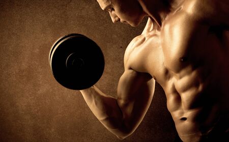Muscular fit bodybuilder athlete lifting weight on grungy backgroundの写真素材