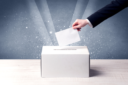 Ballot box with person casting vote on sparkling backgroundの写真素材