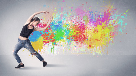 A funky contemporary hip hop dancer dancing in front of grey background with colorful bright paint splatter conceptの写真素材
