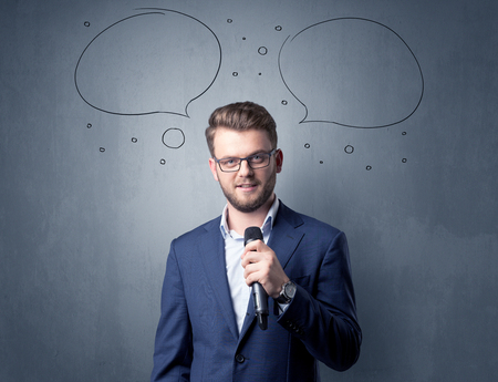 Businessman speaking into microphone with speech bubbles over his headの写真素材