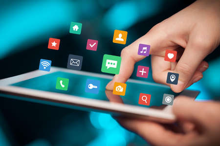 Female hands touching tablet with colorful applicationsの写真素材