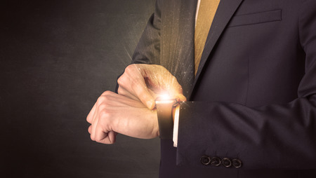 Businessman wearing smartwatch with shiny rays on it.の写真素材