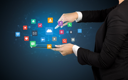 Female hand touching tablet with application icons aboveの写真素材
