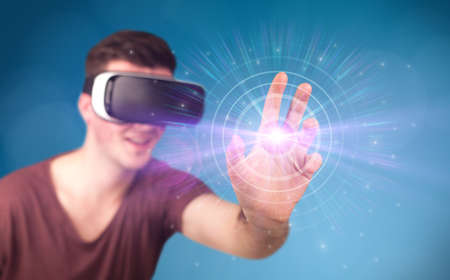 Young impressed man wearing virtual reality goggles with blue circles around his finger 