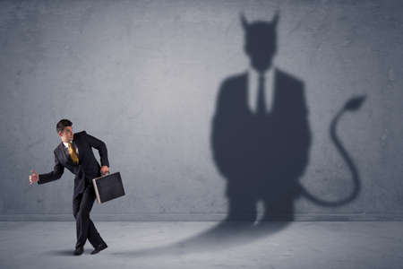 Business man looking at his own devil demon shadow concept backgroundの写真素材