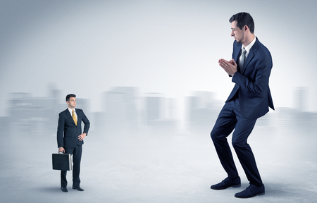 Giant businessman being afraid of small serious executor with suitcaseの写真素材