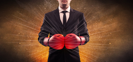 A successful powerful business person in red boxing gloves concept with illustrated power lines and pieces falling apart in front of explosion.の写真素材