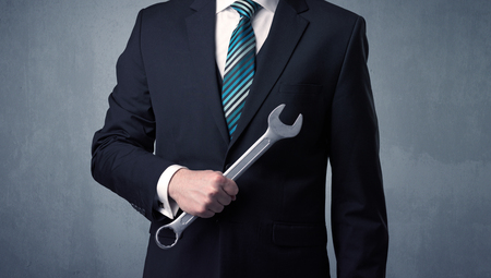Young, handsome, cute businessman holding tool with grey backgroundの写真素材