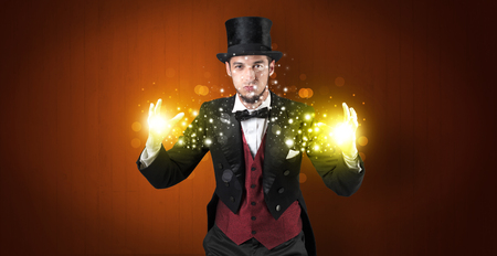 Handsome illusionist holding his superpower on his hands with gold wallpaperの写真素材