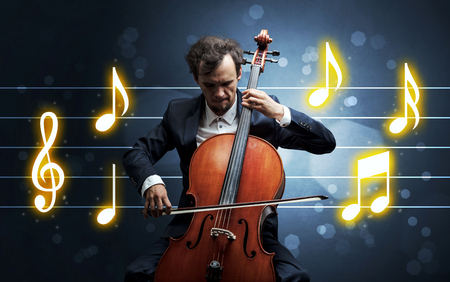 Young handsome cellist playing with music sheet backgroundの写真素材