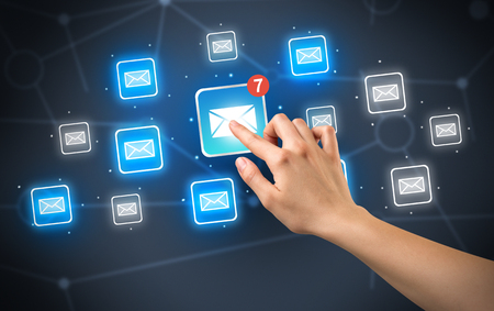Female hand touching unread mail icon with more envelope icons around it の写真素材