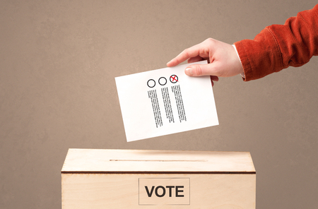 Close up of male hand putting vote into a ballot boxの写真素材