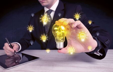 A creative businessman has a bright idea concept with office worker holding light bulb in foreground.の写真素材