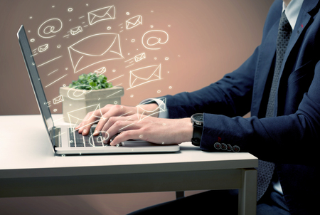 An office worker sending emails and communication with clients with the help of a portable laptop on desk conceptの写真素材