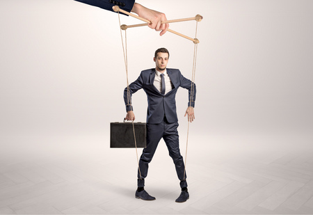 Puppet businessman leaded by a huge handの写真素材