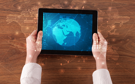 Hand holding tablet with global reports and stock market change conceptの写真素材